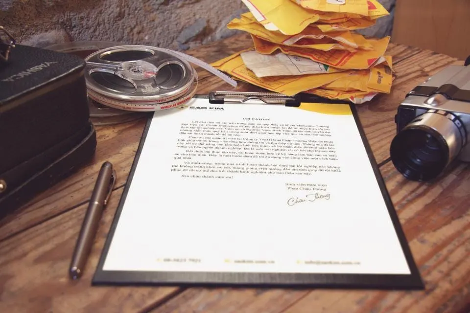 Printed letter on a clipboard beside a pen on a desk