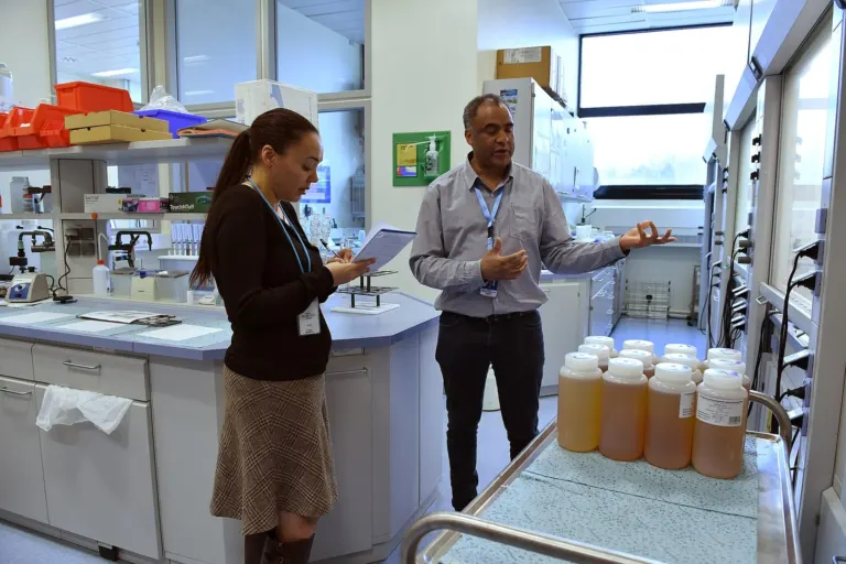 Two colleagues reviewing notes while walking through a laboratory