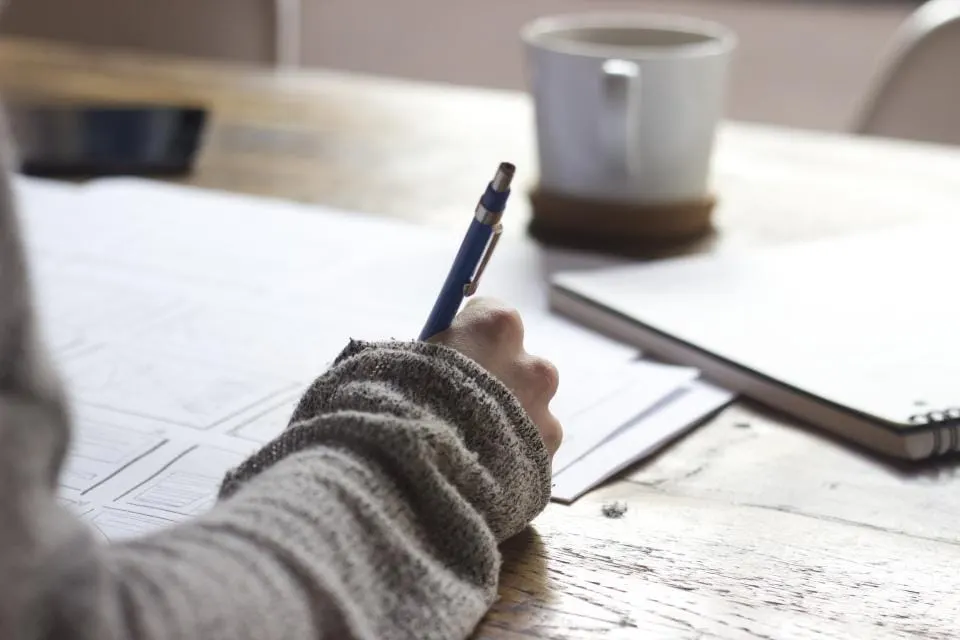 Person writing notes on paper at a desk