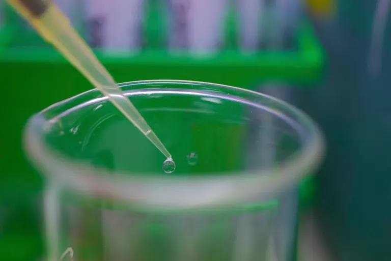 Close-up of a pipette tip releasing a drop of liquid